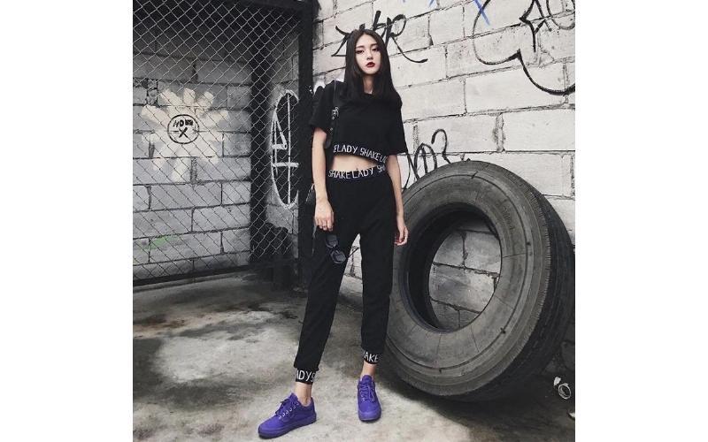 Một phụ nữ trẻ đang tạo dáng với chiếc áo khoác kaki nữ có nón dáng dài màu xanh rêu, thể hiện phong cách thời trang đường phố hiện đại và tự tin.