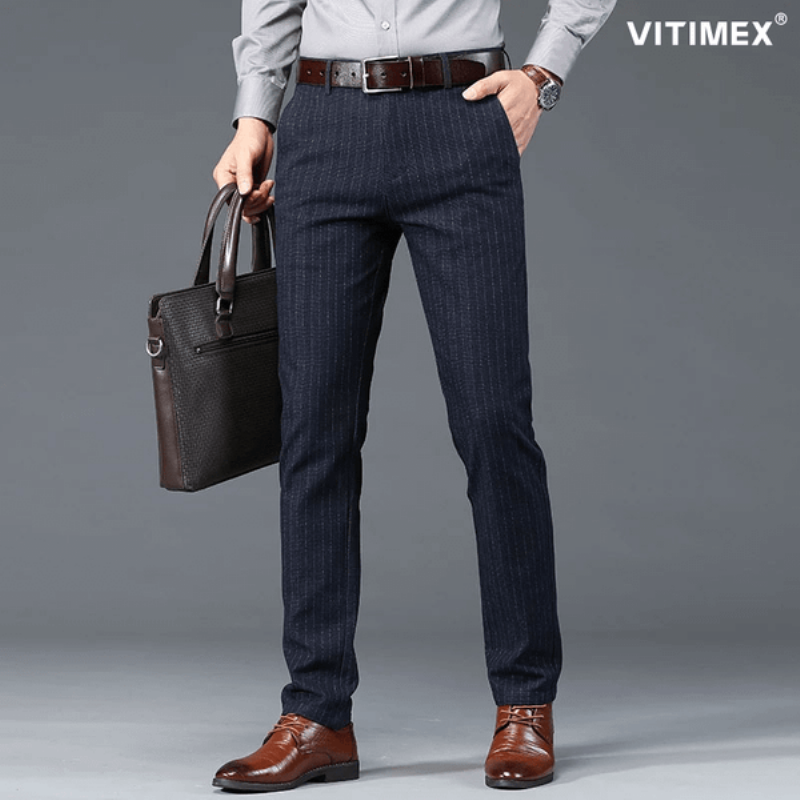 Một người đàn ông đang xem xét kỹ lưỡng đường may và chất liệu của chiếc quần âu nam ống đứng màu xám, thể hiện sự chú ý đến chi tiết và chất lượng sản phẩm.