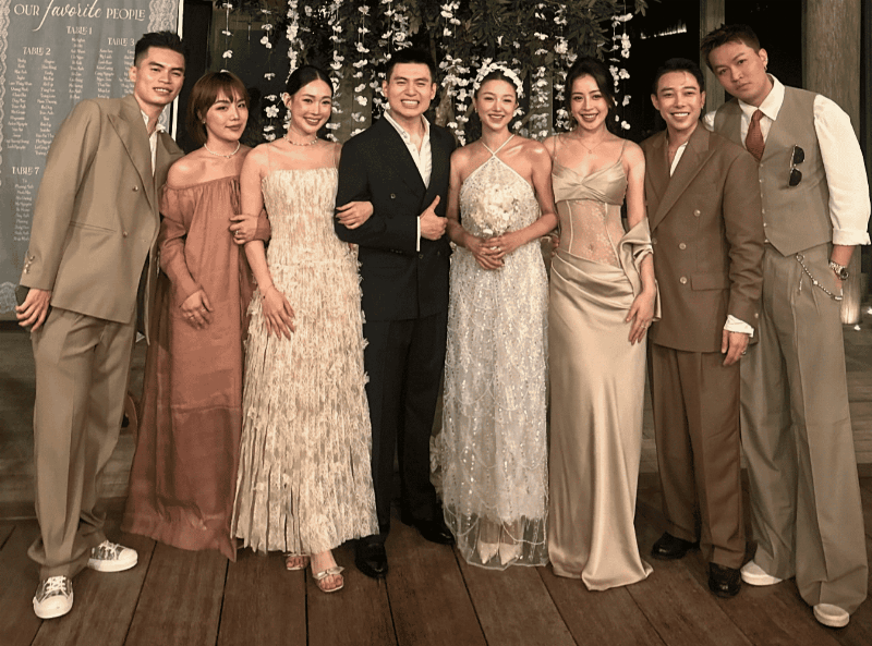 Hình ảnh một người phụ nữ mặc đầm cocktail màu xanh ngọc lịch sự, cười tươi, tham dự tiệc cưới với phong cách thời thượng.