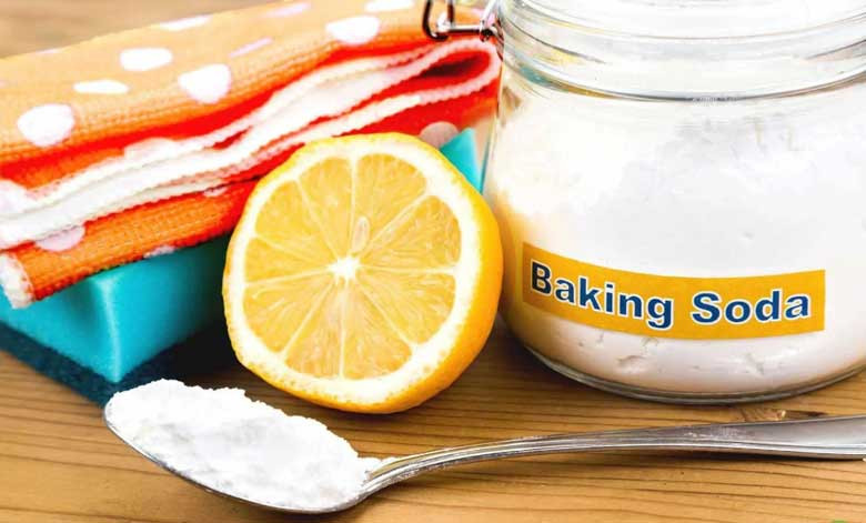 Bột baking soda và chanh tươi trên bề mặt vải trắng, minh họa cách tẩy áo trắng dính màu hiệu quả.