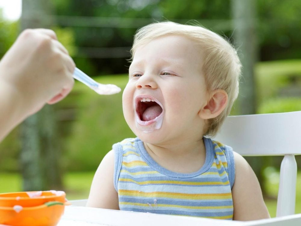 Bé gái đang ăn váng sữa, minh họa câu hỏi về tác hại của váng sữa khi lạm dụng.