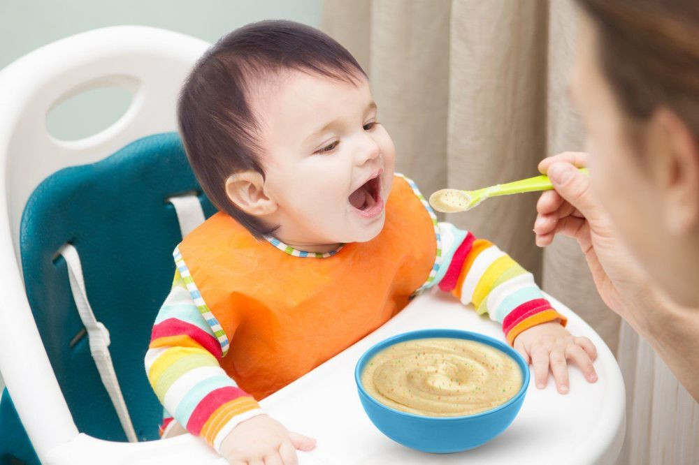 Hình ảnh một bé đang ăn dặm, minh họa thắc mắc về việc sử dụng dầu ăn dặm cho bé