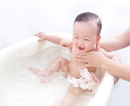 Bé sơ sinh đang tắm trong chậu nước, hình ảnh minh họa tần suất tắm phù hợp cho trẻ để tránh khô da